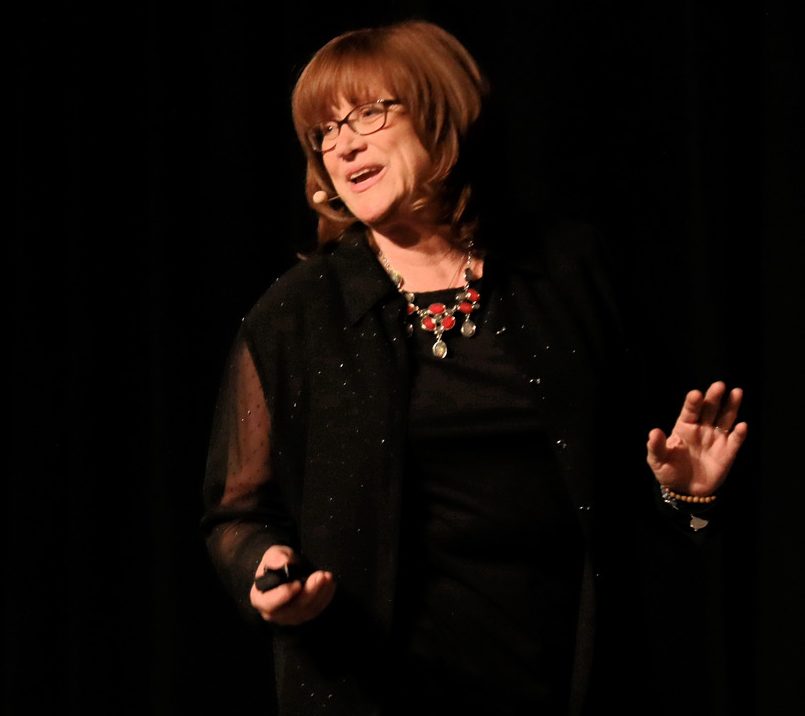 Cirina Catania on stage, arms wide, mid-keynote